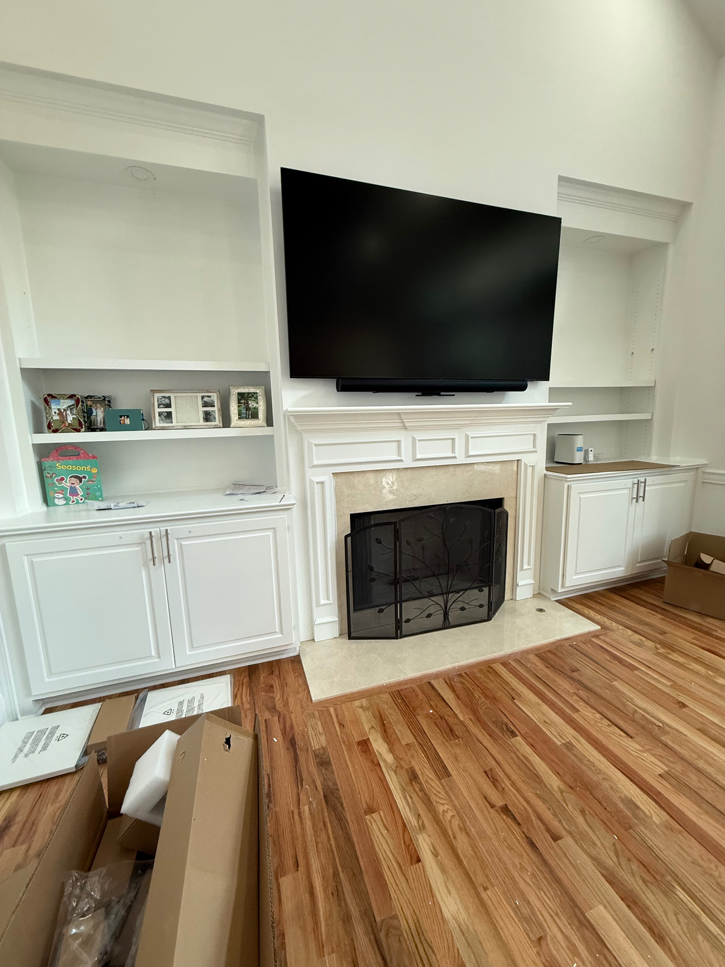 TV mounted above fireplace with white built-in cabinets in Cumming, GA home