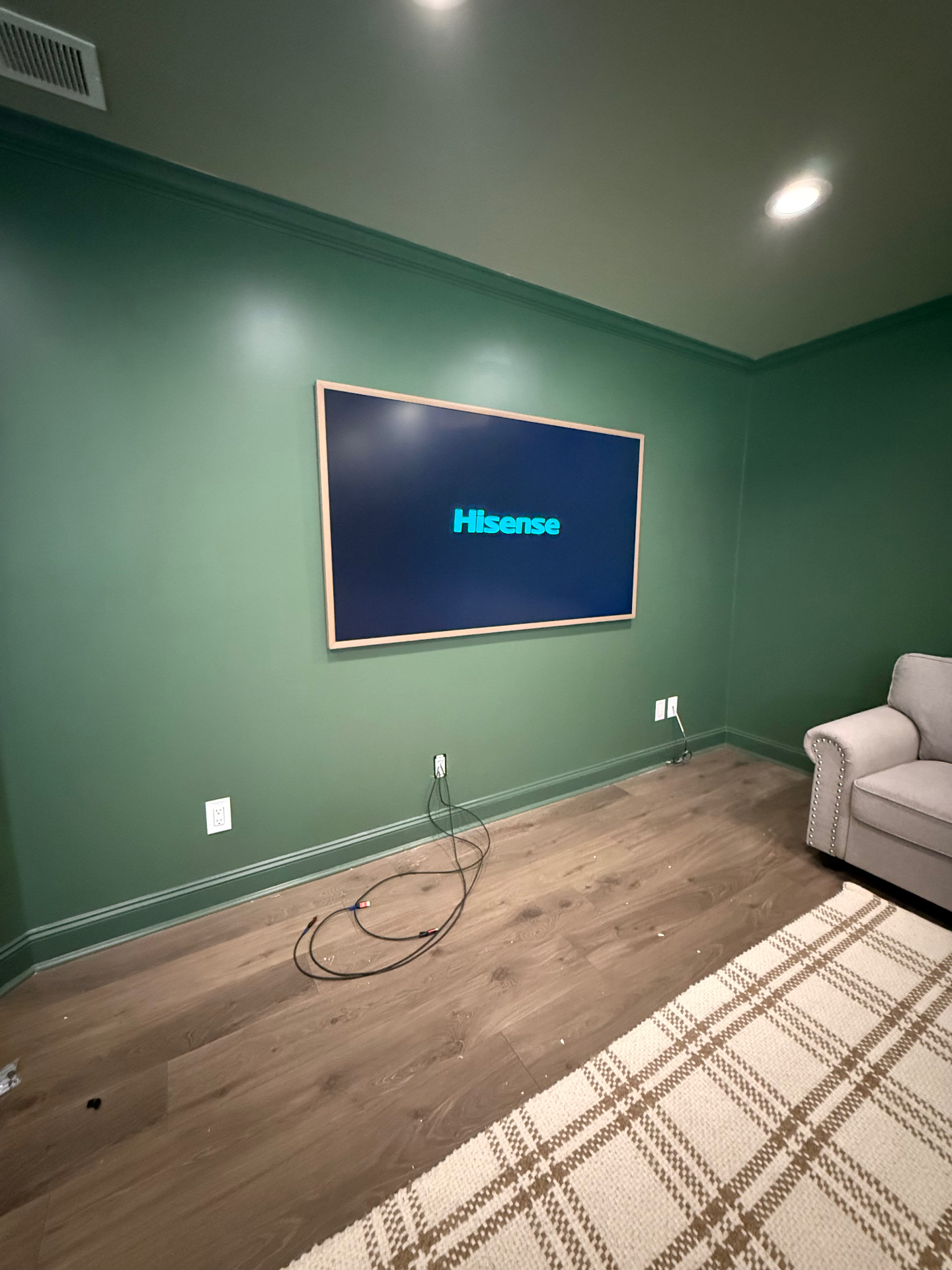 Hisense Canvas TV flush-mounted on green accent wall with visible setup cables in Metro Atlanta media room