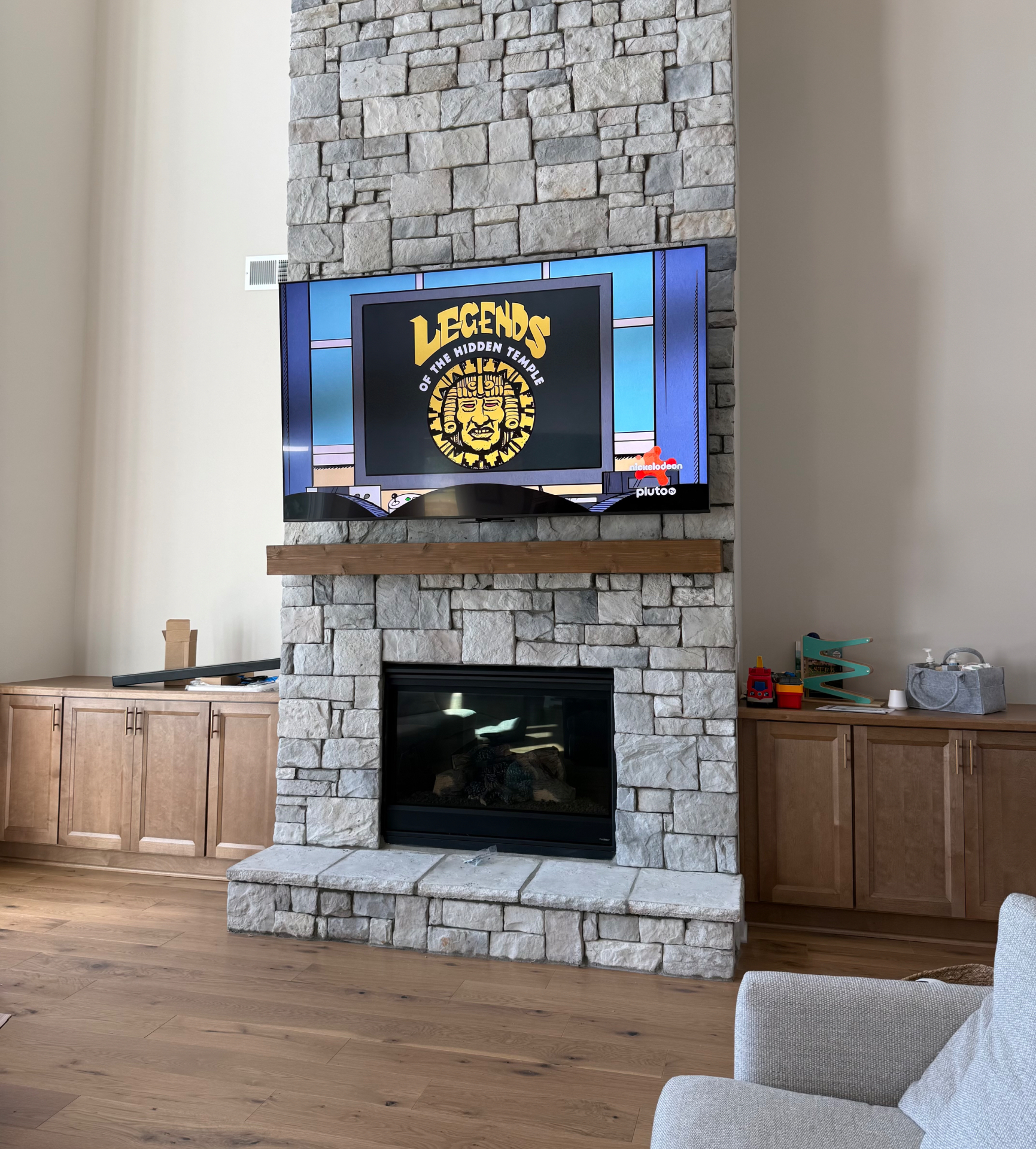 MantelMount pull-down TV mount lowered to eye level on stacked stone fireplace in Metro Atlanta home