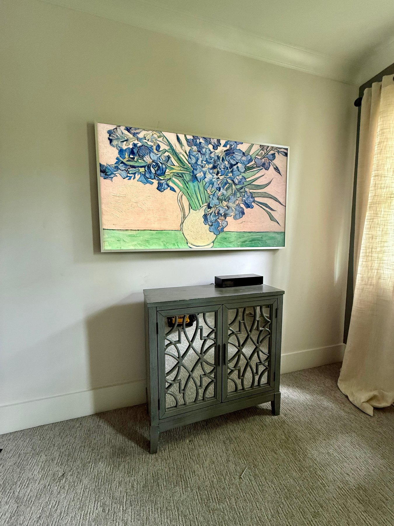 Samsung Frame TV installed in a bedroom with Art Mode artwork, hidden wiring, and a cabinet below the TV