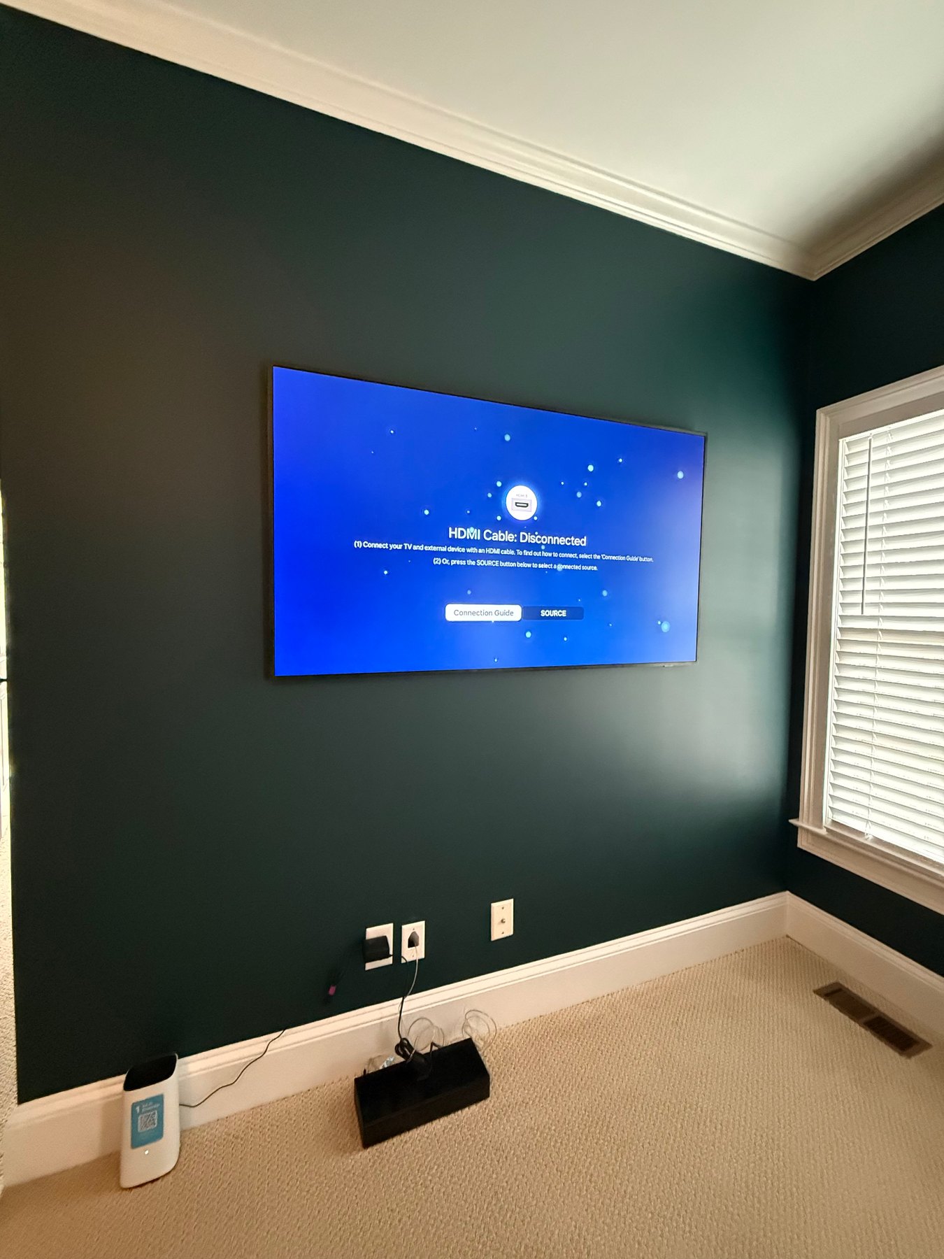 Samsung Frame TV on a green accent wall during One Connect setup with clean wall-mounted placement